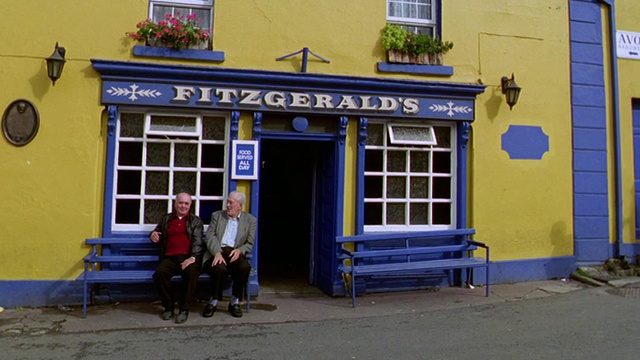图为爱尔兰艾沃萨“菲茨杰拉德”酒吧前两名年长男子坐在长凳上的肖像视频素材