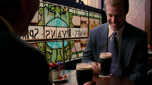 在爱尔兰的都柏林，两名商人坐在靠窗的桌旁，喝着啤酒聊天视频素材