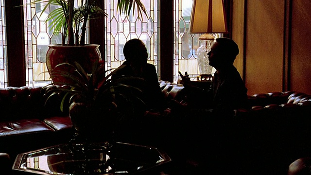 缓慢放大两个商人的剪影坐在沙发上聊天在布朗宫殿酒店大厅/丹佛，CO视频下载