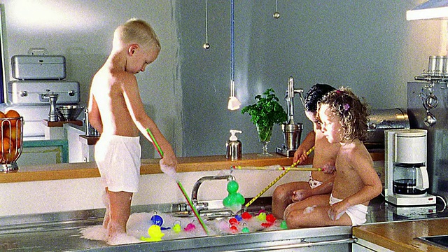 三个赤膊的孩子在肥皂水池里捞塑料鸭子视频素材