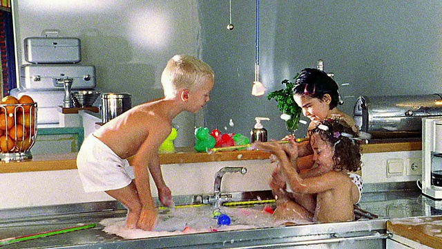 镜头拉近，三个赤膊的孩子在肥皂水池里互相泼水视频素材