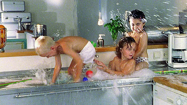 三个赤膊的孩子在有肥皂的水池里互相泼水视频素材