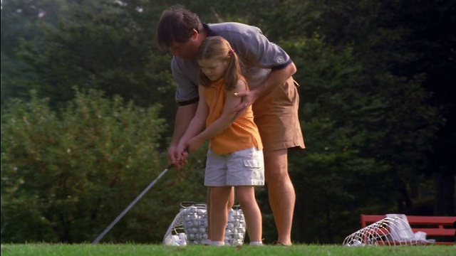 男子在高尔夫球场向女孩展示正确的高尔夫挥杆视频下载