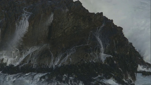 在新西兰，暴风雨的海浪翻滚到多岩石的海岸视频素材