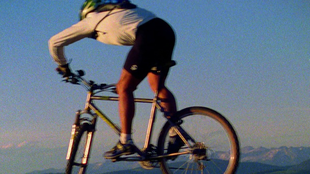 慢镜头男性山地自行车在镜头前跳跃，背景是山脉/科罗拉多西部视频素材