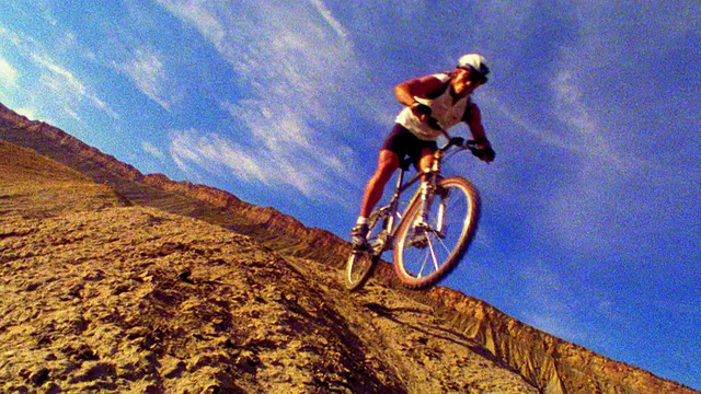 倾斜慢动作男性山地自行车跳过土丘与高原的背景/西部科罗拉多视频下载