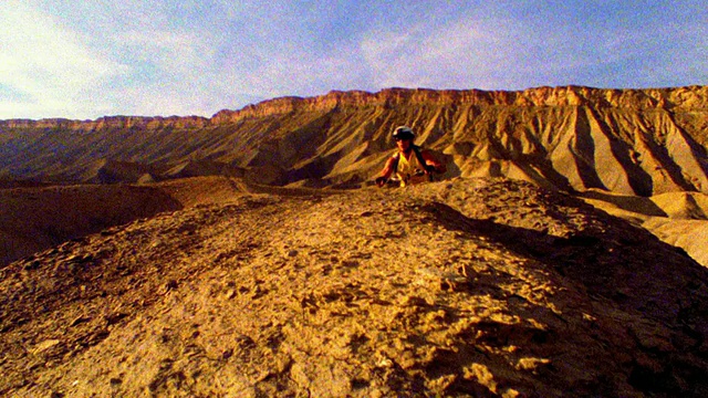 慢动作起重机拍摄的男性山地摩托车跳过土丘的高原背景/科罗拉多州西部视频素材