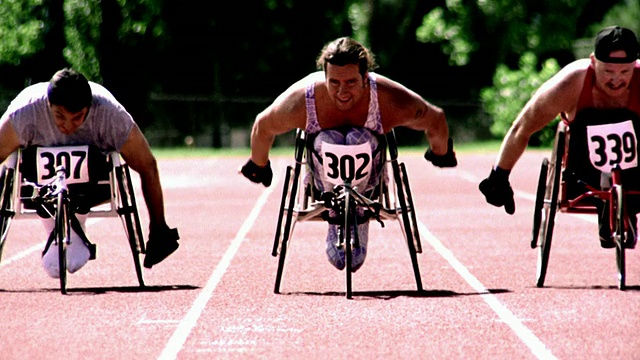 过度曝光选择性对焦慢镜头三个坐在轮椅上的男人向赛道上的摄像机跑去视频下载