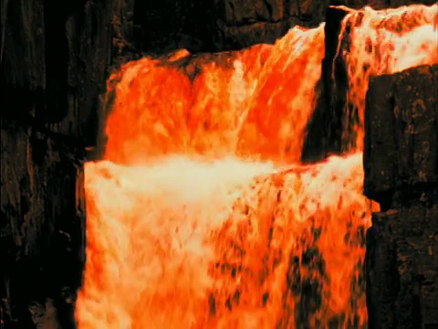 近距离倾斜瀑布与橙色的水落入河/高力量，蒂斯代尔，英国视频下载