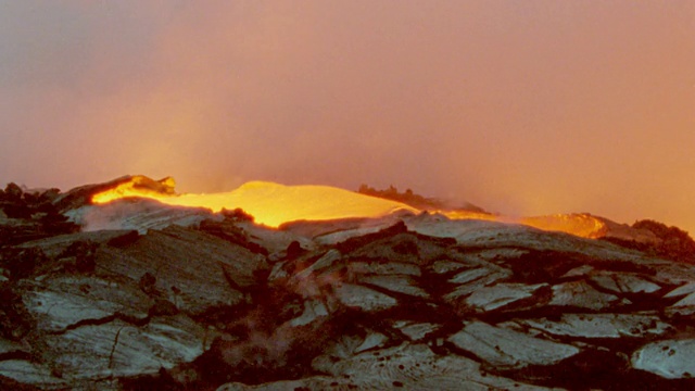夏威夷基拉韦厄火山，炽热炽热的熔岩在冷却的黑色熔岩顶部流动，喷出浓烟视频素材
