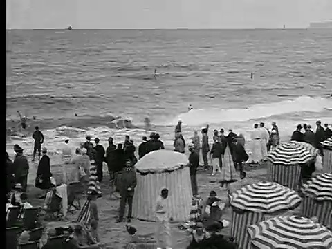 20世纪20年代PAN伞状帐篷+海滩上的人群/人们在海浪中游泳/法国多维尔视频下载