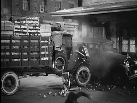 20世纪20年代/30年代的一辆满载农产品的卡车撞上了停在城市街道上的汽车，前景中有个人倒下视频素材