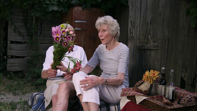 一个浪漫的老人用一束花给妻子惊喜的慢静态镜头视频素材
