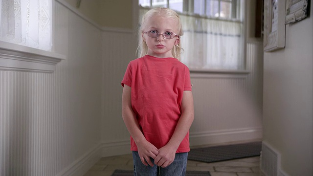 一个戴着人工耳蜗的金发小女孩站在走廊里视频素材