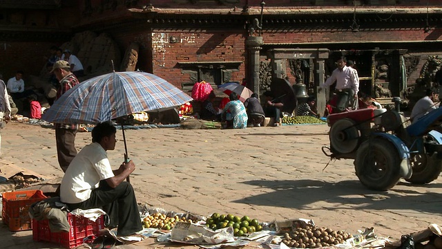 一名尼泊尔男子坐在市场的伞下。视频素材