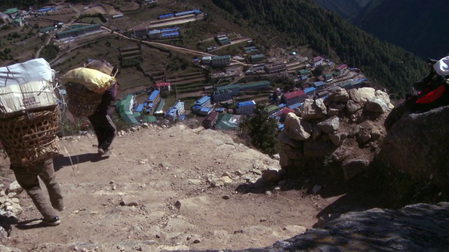 尼泊尔的夏尔巴人提着篮子走向纳姆切集市。视频下载