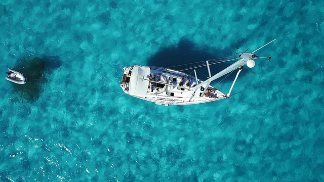 航拍俯视在美丽清澈的蓝色海洋中抛锚的帆船视频素材