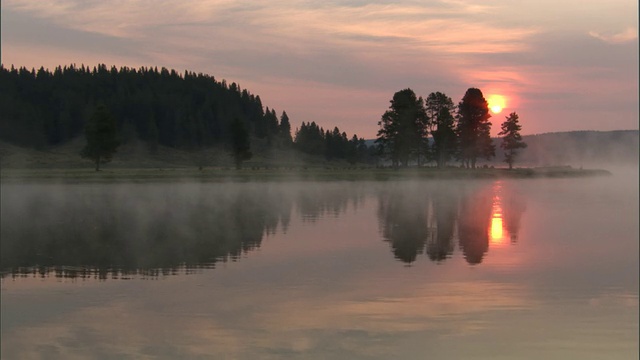 日落时，薄雾飘过树木和湖泊，美国黄石公园视频素材