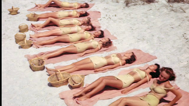 20世纪40年代/50年代的高角线妇女在相同的泳衣躺在沙滩上的毛巾上翻到腹部视频下载