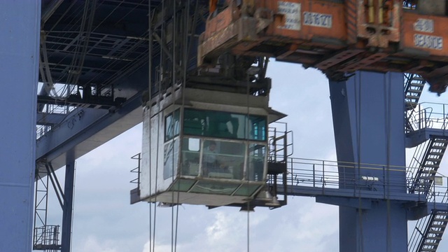 在中国的一个港口，门式起重机正横挂在一艘集装箱船的甲板上视频下载