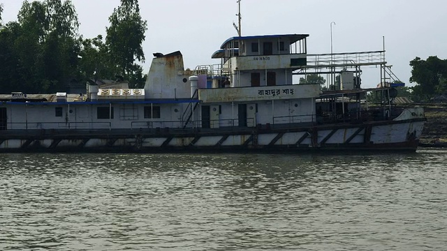从孟加拉国三角洲的一艘快艇上看到的景象，这艘快艇正驶过停泊在河岸的传统木船视频下载