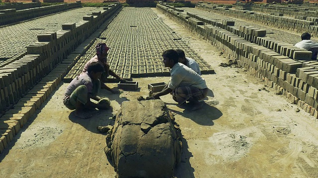 孟加拉国的年轻人用简单的木模具将简单的粘土和水混合制成砖块，动作快速而有节奏视频下载