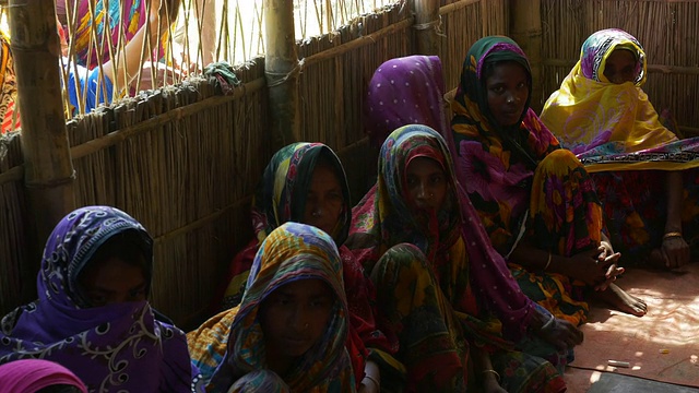 孟加拉国北部一个小村庄的妇女们穿着鲜艳的纱丽，聚集在茅草会议室里，听取非政府组织的医疗建议视频下载