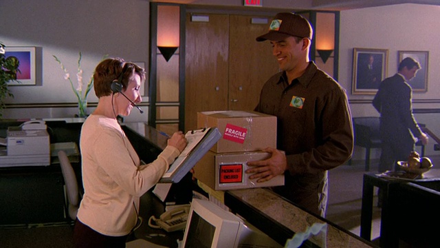 送货员将2个箱子送到办公室的前台/戴耳机的女士签收包裹视频下载