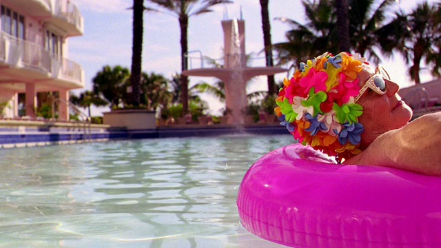 MS资深女性在太阳镜+多彩的花泳帽放松在粉红色内胎在游泳池视频下载