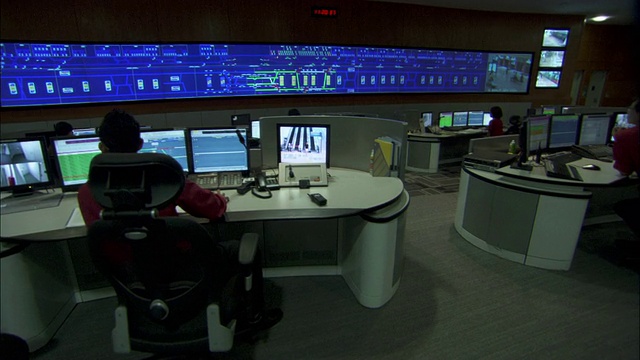 技术人员使用计算机和一个大型监视监视器在多个工作站工作。视频下载
