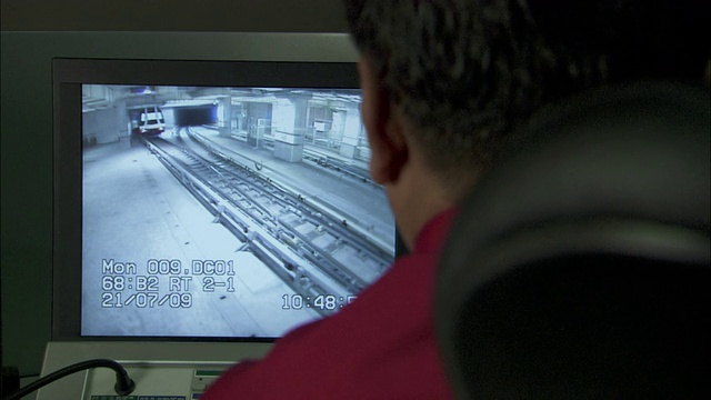 一名男子在电脑屏幕上观看一列客运列车通过。视频素材