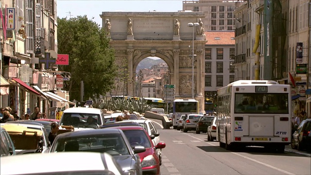 行人穿过马赛一座凯旋门附近繁忙的城市街道。视频下载