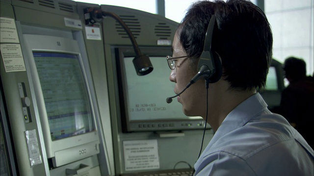 一位专家戴着耳机，看着显示器上闪烁的信息。视频下载