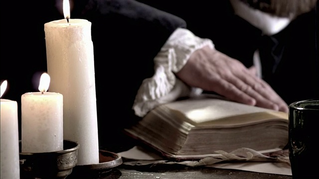 诺查丹玛斯在烛光下翻动书页。视频素材
