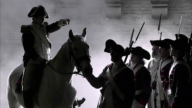 一位骑着白马的军事领袖正在向穿着法国大革命制服的士兵下达命令。视频下载