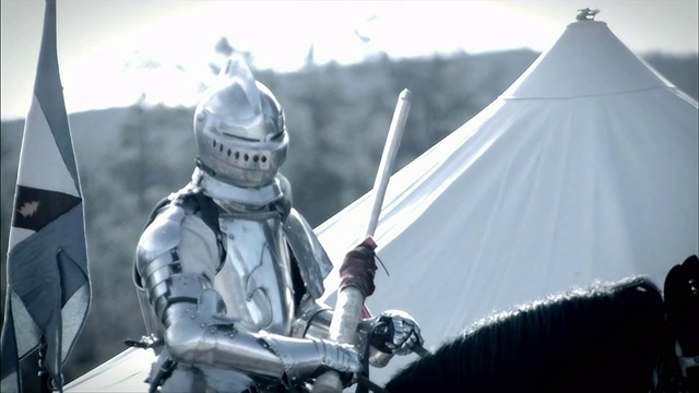 一个骑在马上的骑士穿着一套盔甲靠近一个白色的帐篷。视频素材
