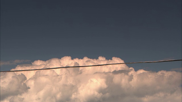 一根电线在蓬松的云层前延伸。视频下载