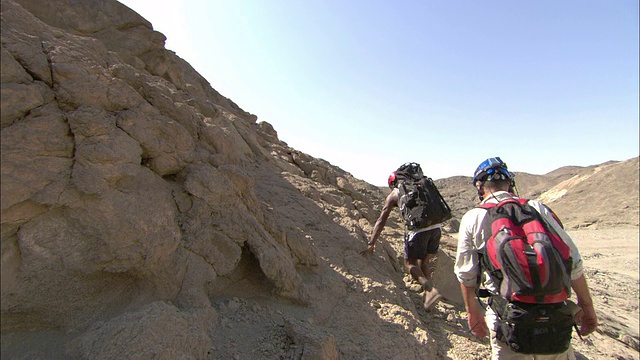 在埃及的一个考古遗址，徒步旅行者爬上一个岩石山坡。视频素材