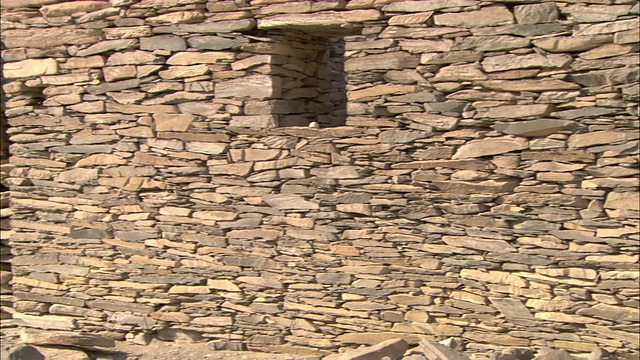 堆砌的石墙的废墟靠近一个有门窗开口的石头结构。视频素材