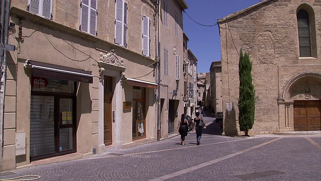 行人走在一座石砌教堂旁边的小巷里。视频素材