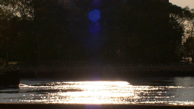 当轮船在水面上游弋，车辆经过附近时，河水会反射阳光。视频素材