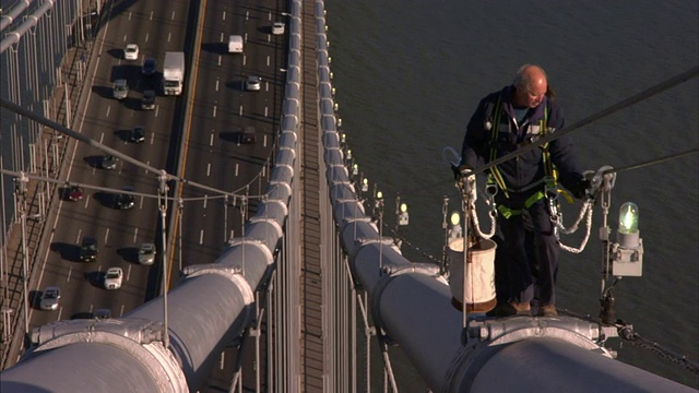 在纽约市，一名维修工人爬上一座吊桥进行维修。视频素材