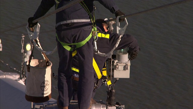 维修工人在纽约市的一座吊桥上换灯。视频素材
