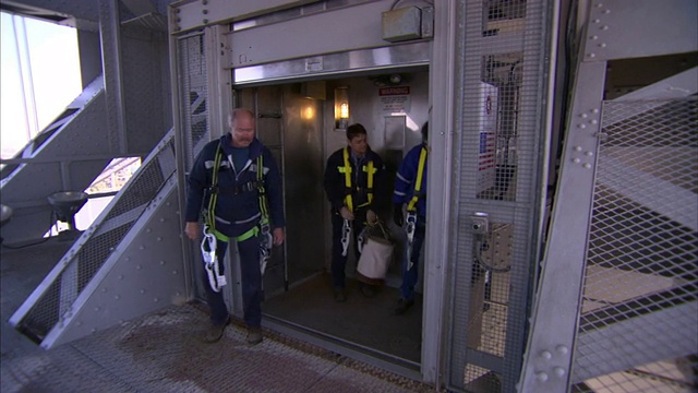 在纽约市的一座悬索桥上，维修工人从服务电梯里出来。视频下载