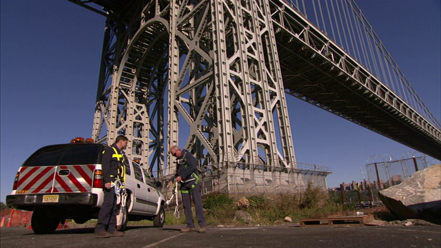 维修工人站在纽约市一座悬索桥的基座上装备自己。视频素材