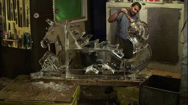 一位艺术家正在凿一个冰雕，同时一位工人将冰块扔进一个储存罐。视频素材