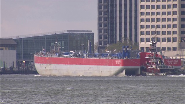 一艘驳船驶过纽约市的滨水摩天大楼。视频素材
