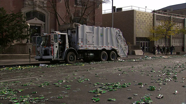 在纽约市，翻斗卡车在树叶和垃圾遍地的街道上行驶。视频素材