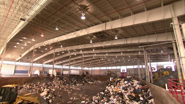推土机将垃圾倾倒到一个大型收集设施的垃圾堆中。视频下载