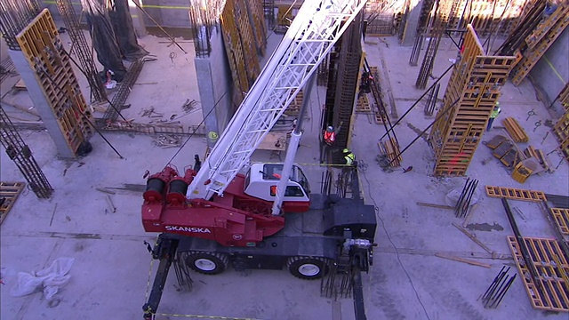 起重机和建筑工人在一个大型建筑地盘作业。视频素材